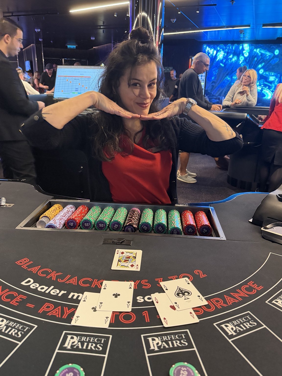 A casino crew member posing behind a blackjack table