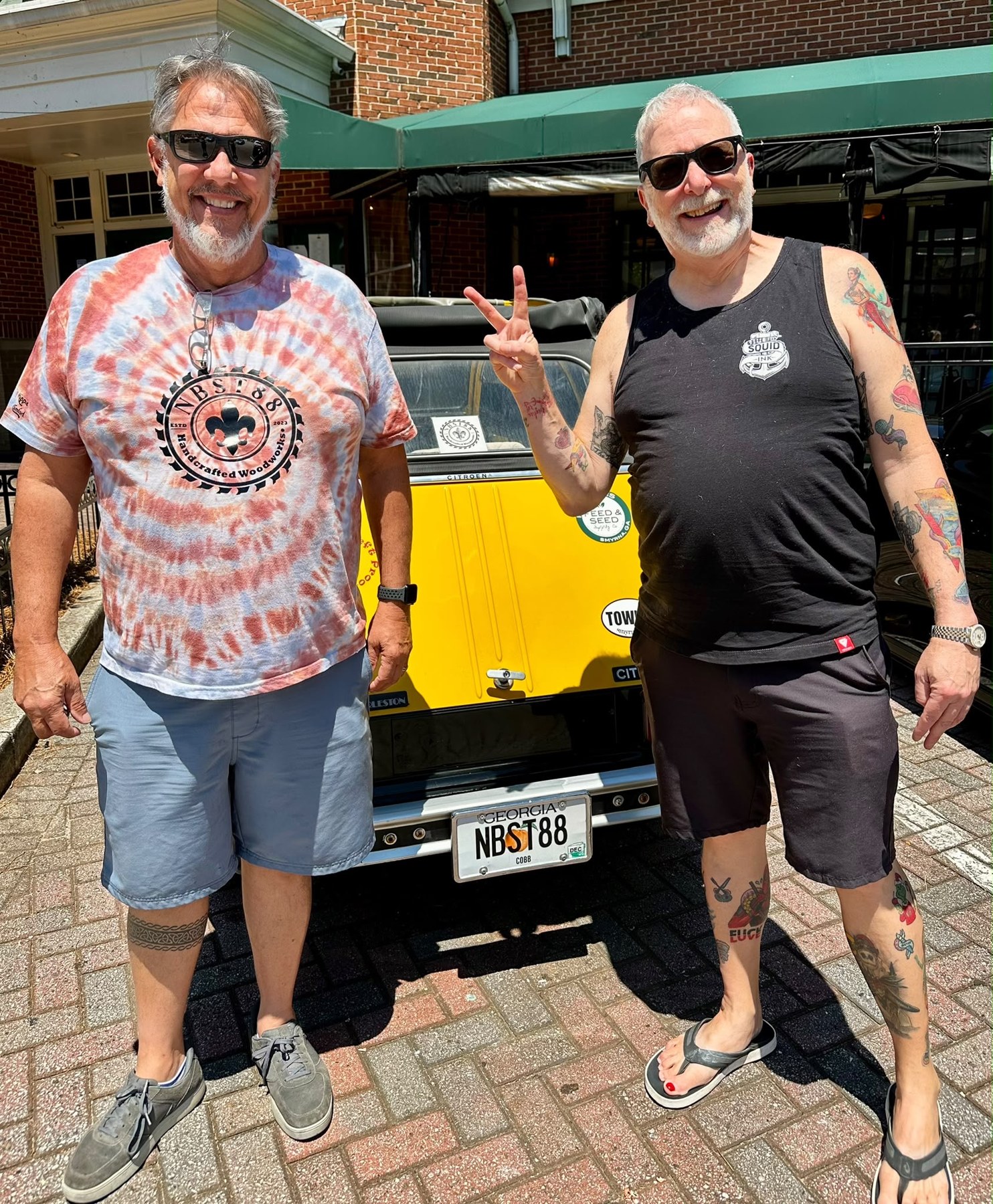 Steven and Mark smiling beside a yellow vehicle in Atlanta